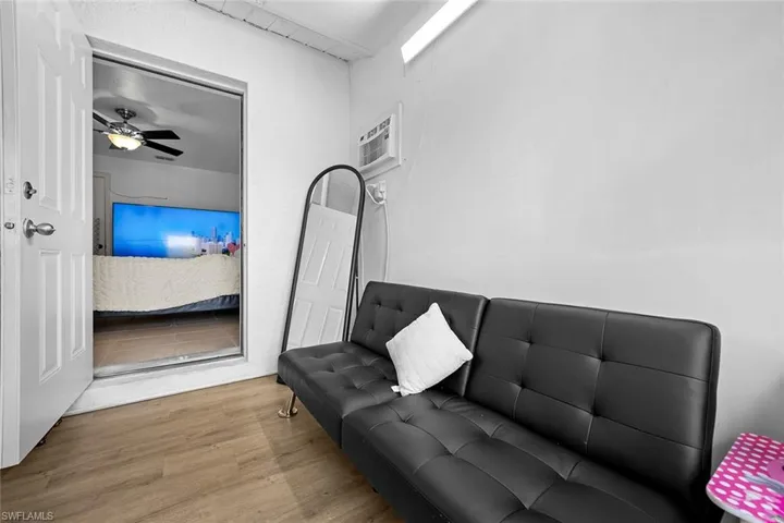 Living area featuring wood finished floors, a ceiling fan, and a wall mounted air conditioner