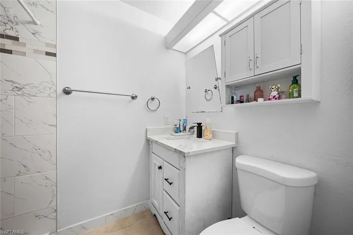 Full bath with vanity, a textured wall, and light tile patterned floors