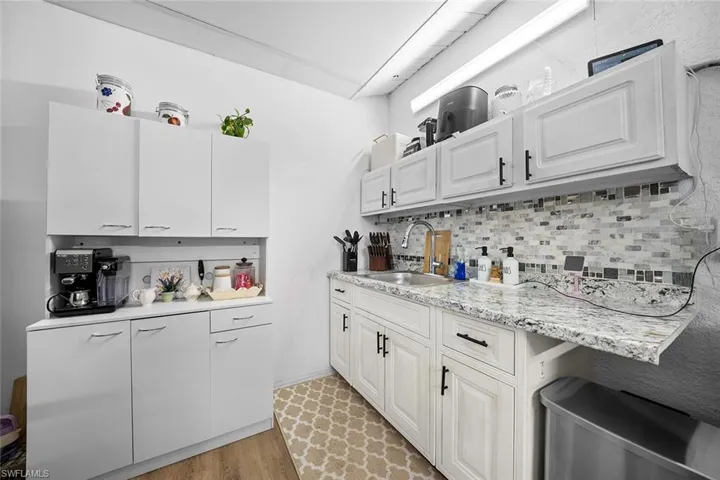 Kitchen featuring light wood finished floors, white cabinets, tasteful backsplash, and light stone counters