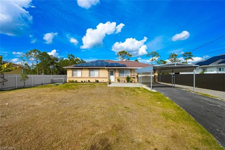 View of front of house featuring solar panels, a detached carport, stucco siding, and asphalt driveway