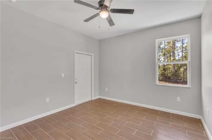 Empty room featuring wood finished floors, ceiling fan, and baseboards