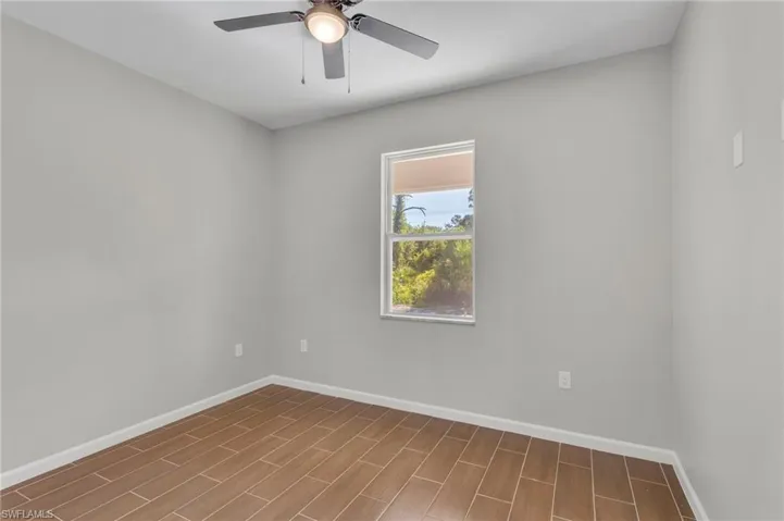 Spare room with baseboards, wood finished floors, and ceiling fan