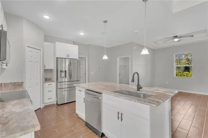 Kitchen featuring an island with sink, wood finish floors, recessed lighting, a sink, and stainless steel appliances