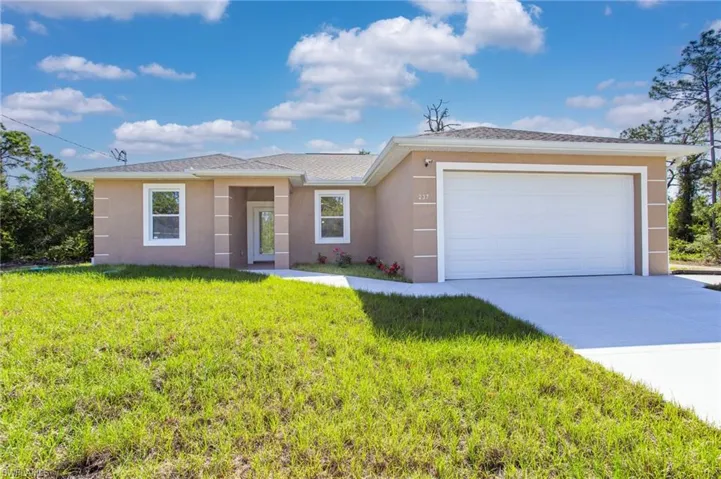 Single story home featuring a garage, a front yard, driveway, and stucco siding