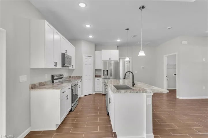 Kitchen with a sink, baseboards, appliances with stainless steel finishes, and wood finish floors