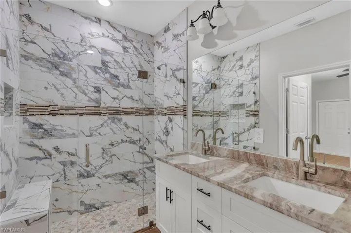 Bathroom featuring visible vents, a sink, and a marble finish shower