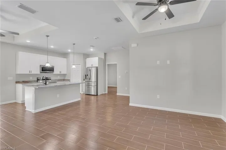 Kitchen featuring stainless steel appliances, visible vents, a tray ceiling, and a ceiling fan