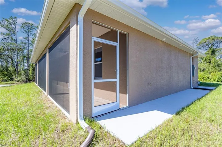 View of side of home featuring a sunroom, a yard, and stucco siding