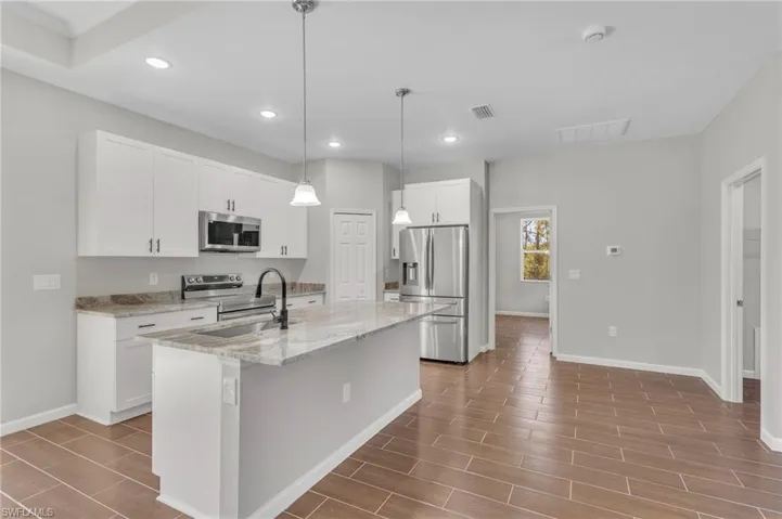 Kitchen featuring visible vents, baseboards, appliances with stainless steel finishes, recessed lighting, and a center island with sink