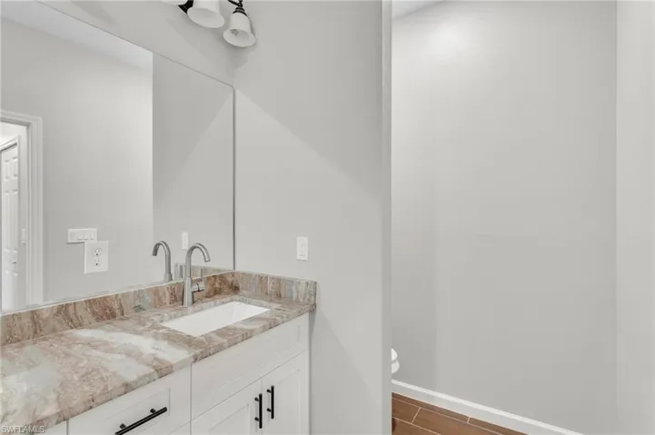 Bathroom featuring toilet, baseboards, vanity, and wood finished floors