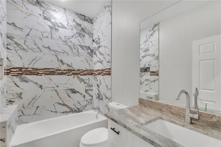 Full bath with toilet, vanity, and washtub / shower combination