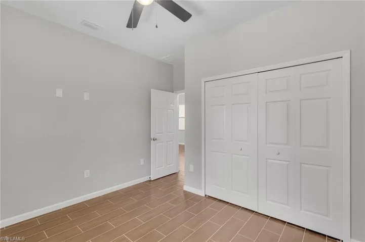 Unfurnished bedroom featuring a closet, baseboards, a ceiling fan, visible vents, and wood finished floors