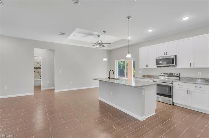 Kitchen with visible vents, a kitchen island with sink, a sink, stainless steel appliances, and a raised ceiling