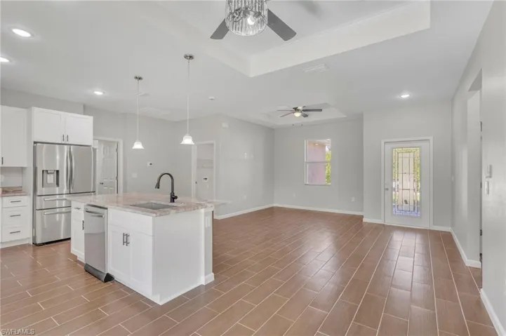 Kitchen with recessed lighting, a ceiling fan, a tray ceiling, stainless steel appliances, and a sink