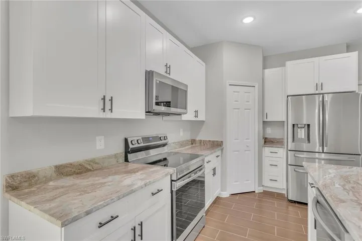 Kitchen featuring white cabinetry, appliances with stainless steel finishes, light stone counters, and recessed lighting