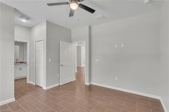 Unfurnished bedroom with baseboards, ceiling fan, a sink, and visible vents