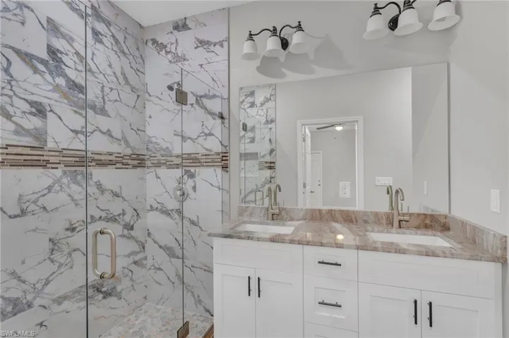 Bathroom with double vanity, a marble finish shower, and a sink