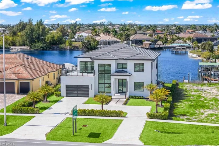 Contemporary house with a front yard, stucco siding, a water view, driveway, and a garage