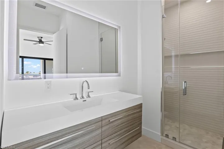 Full bath featuring a stall shower, vanity, and a ceiling fan