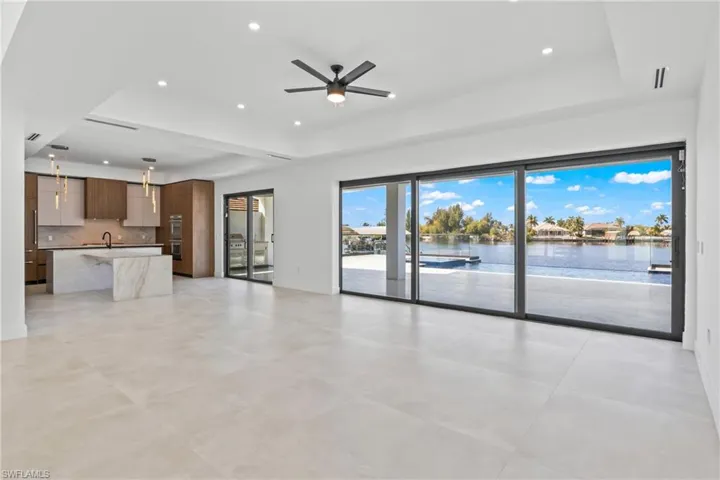 Unfurnished living room featuring ceiling fan, a raised ceiling, recessed lighting, and a water view