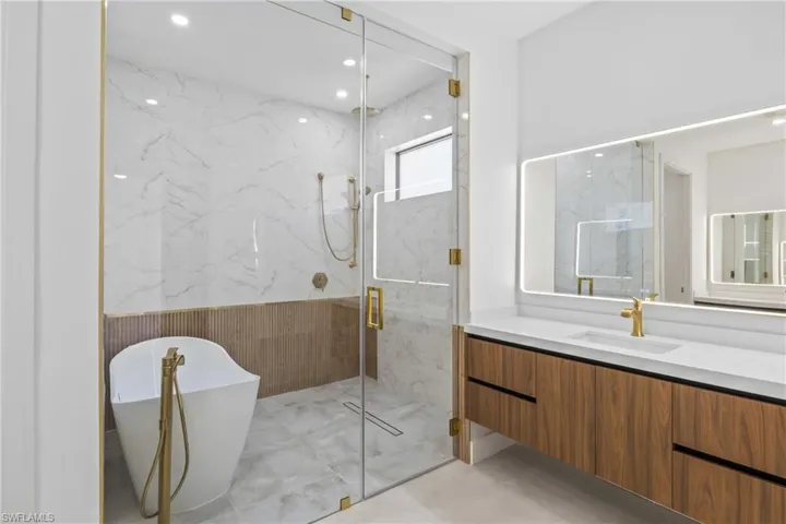 Full bathroom with vanity, a marble finish shower, a soaking tub, and recessed lighting