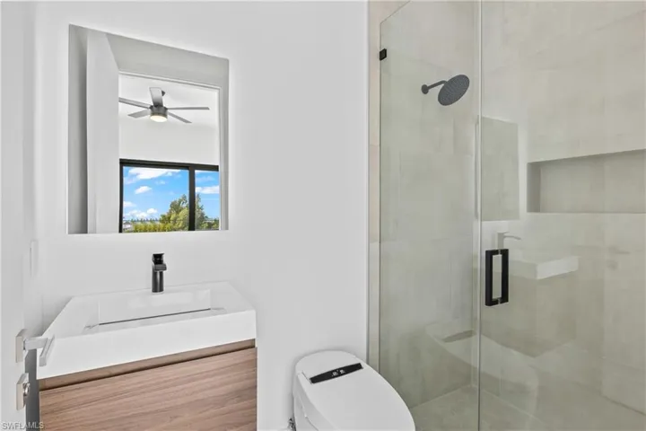 Full bath with vanity, a shower stall, and a ceiling fan