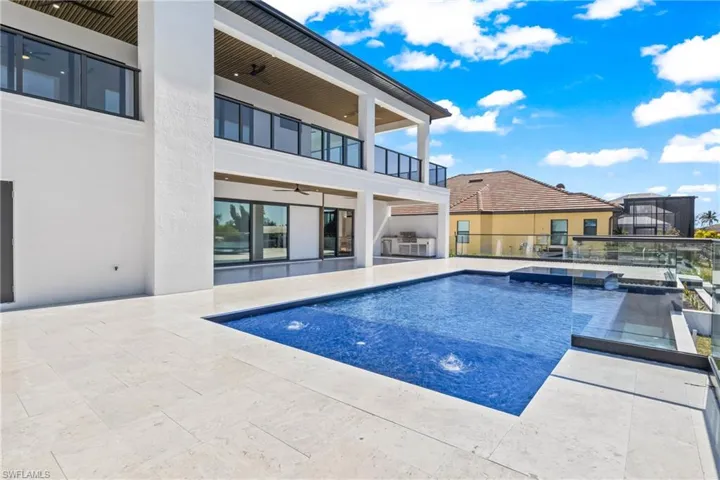 Swimming pool featuring a balcony, a patio area, and a hot tub
