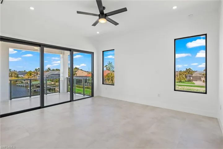 Empty room with ceiling fan, recessed lighting, a residential view, and a water view