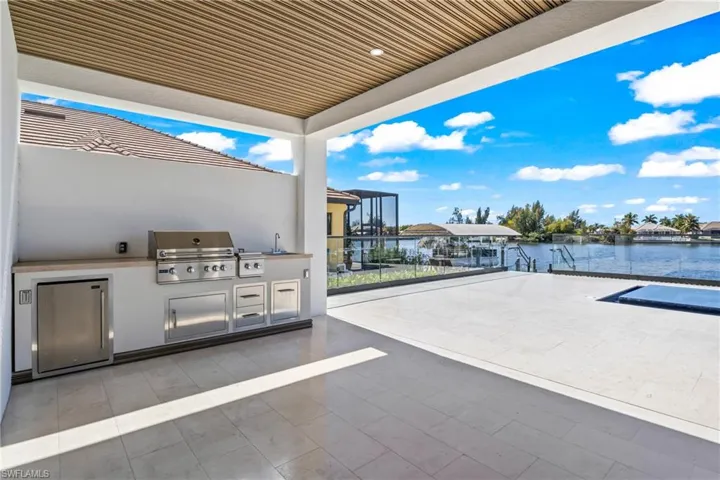View of patio featuring an outdoor kitchen, a water view, and a boat dock