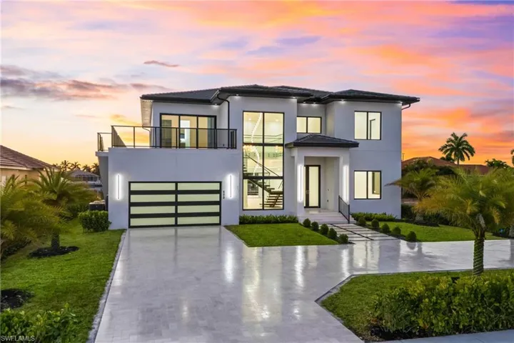Contemporary home with concrete driveway, a lawn, a garage, stucco siding, and a balcony