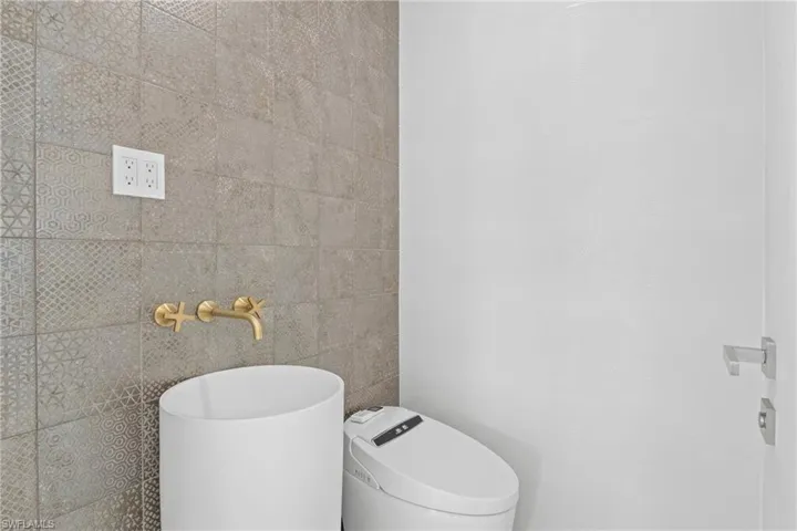 Bathroom with toilet and tile walls