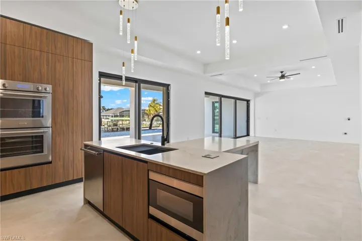 Kitchen with wood finish cabinetry, stainless steel appliances, a raised ceiling, pendant lighting, and healthy amount of natural light