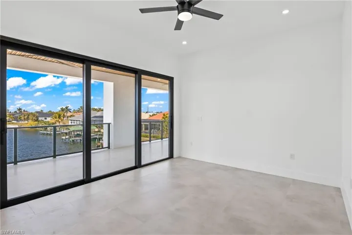Empty room with a water view, ceiling fan, recessed lighting, and a residential view