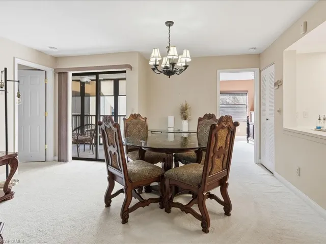 Dining room with light colored carpet and a chandelier