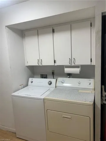 Washroom with cabinet space, separate washer and dryer, and a textured wall