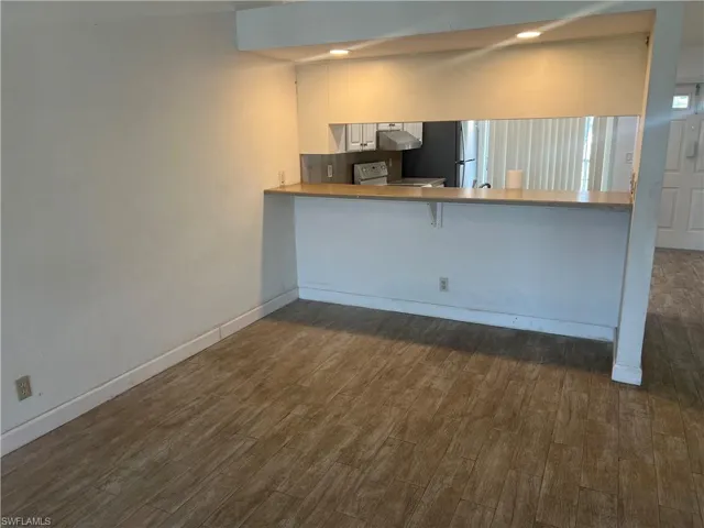 Kitchen featuring a kitchen breakfast bar, white range oven, dark wood-type flooring, a peninsula, and freestanding refrigerator