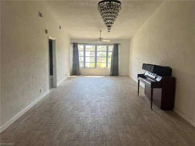 Unfurnished living room with a textured wall, ceiling fan, and wood finished floors