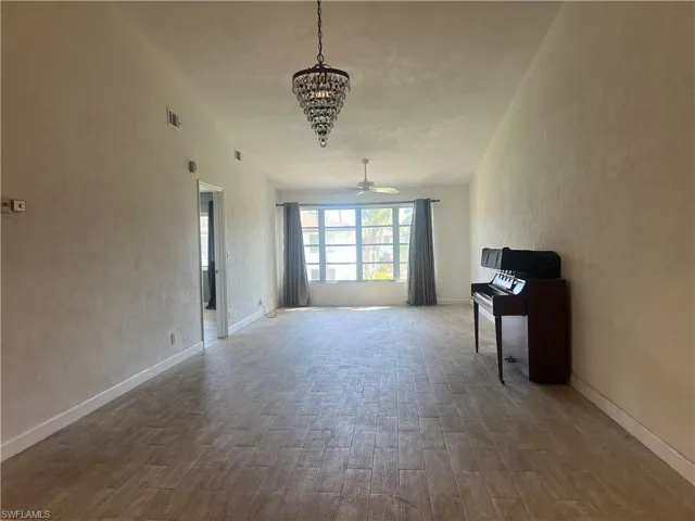 Living room featuring a textured wall, wood finished floors, a ceiling fan, and a chandelier