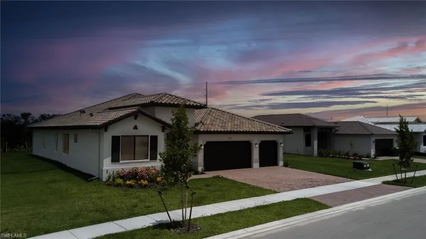 Mediterranean / spanish-style house featuring decorative driveway, a garage, a front lawn, stucco siding, and a tile roof