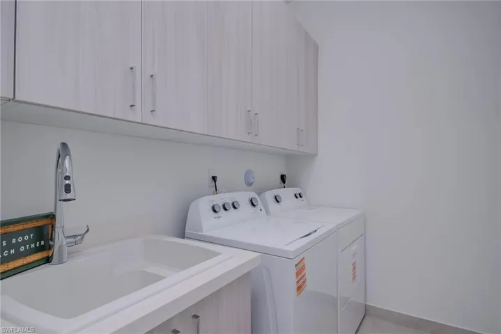 Washroom with cabinet space, washer and dryer, and light tile patterned floors