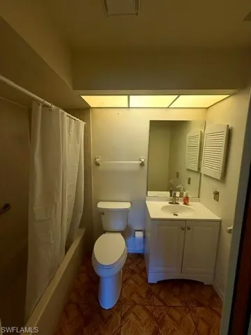 Master Bathroom featuring a white vanity with integrated sink, a rectangular mirror, a white toilet, and a bathtub with tiled surround