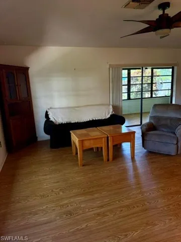 Living area featuring wood-finish flooring, a ceiling fan with integrated lighting, and a glass-enclosed Florida room