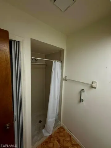 Walk-in shower enclosure with a stainless steel shower rod and a patterned floor