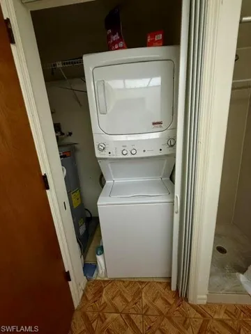 Dedicated laundry closet featuring a white stacked washer and dryer unit, wire shelving, and a water heater