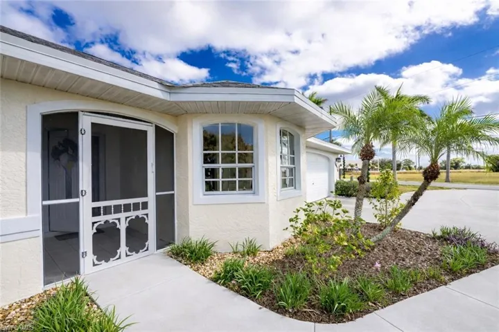 View of side of home with stucco siding, driveway, a sunroom, and a garage