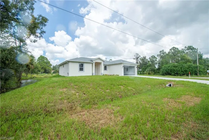 View of front of home with an attached garage, a front lawn, stucco siding, and driveway