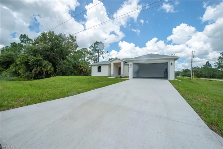 Ranch-style home featuring a front lawn, a garage, driveway, and stucco siding