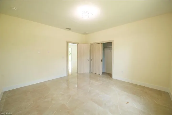 Unfurnished bedroom with a closet and light marble finish floors
