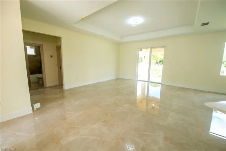 Unfurnished room with a raised ceiling and light marble finish flooring