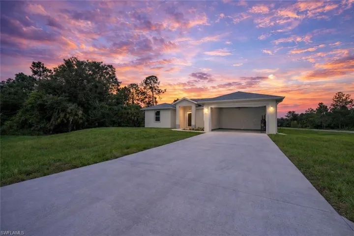 Prairie-style home featuring a yard, a garage, concrete driveway, and stucco siding